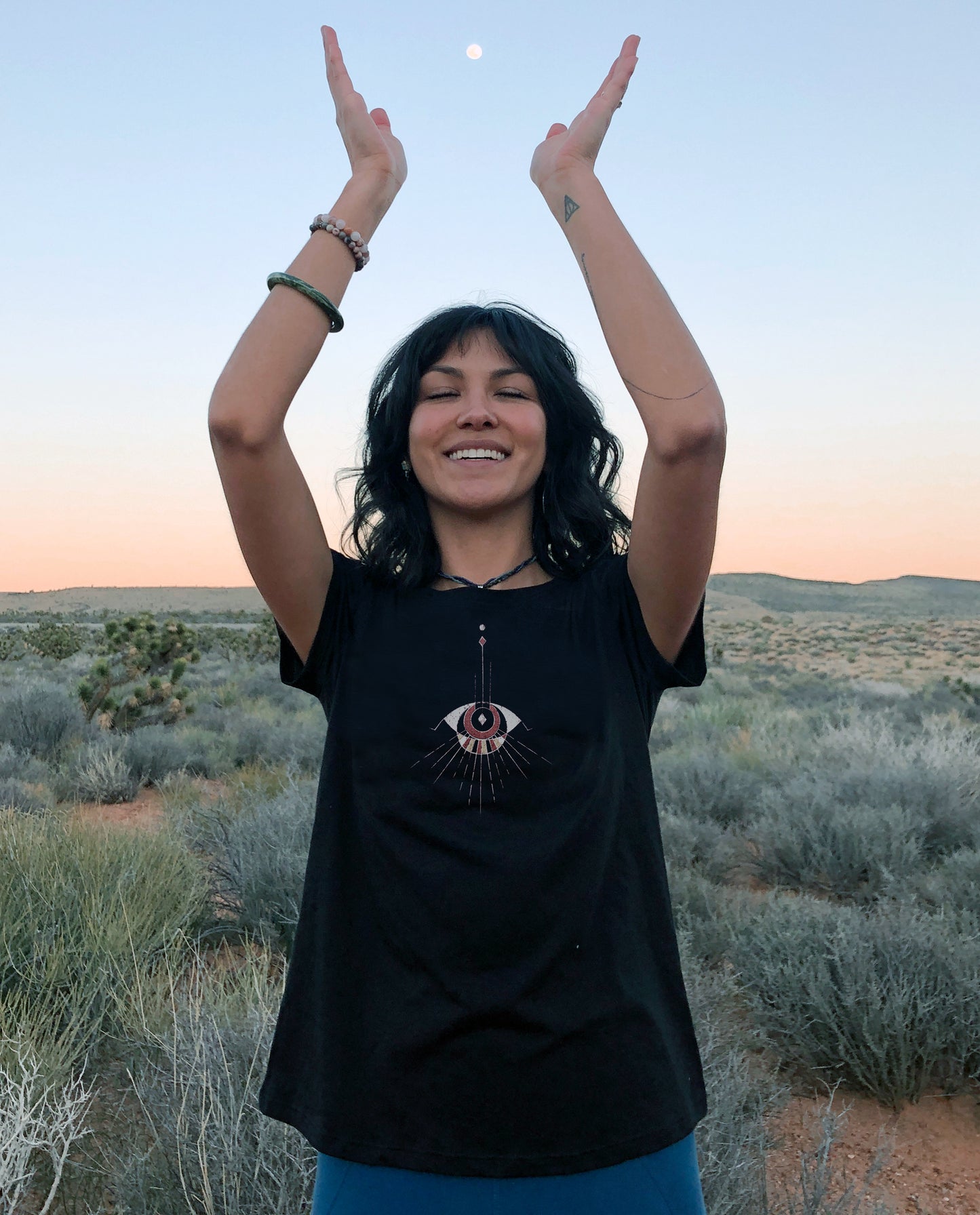 Women wearing comfortable Black Unisex T, Poly Cotton blend.  Abstract Eye pattern draping from neckline.