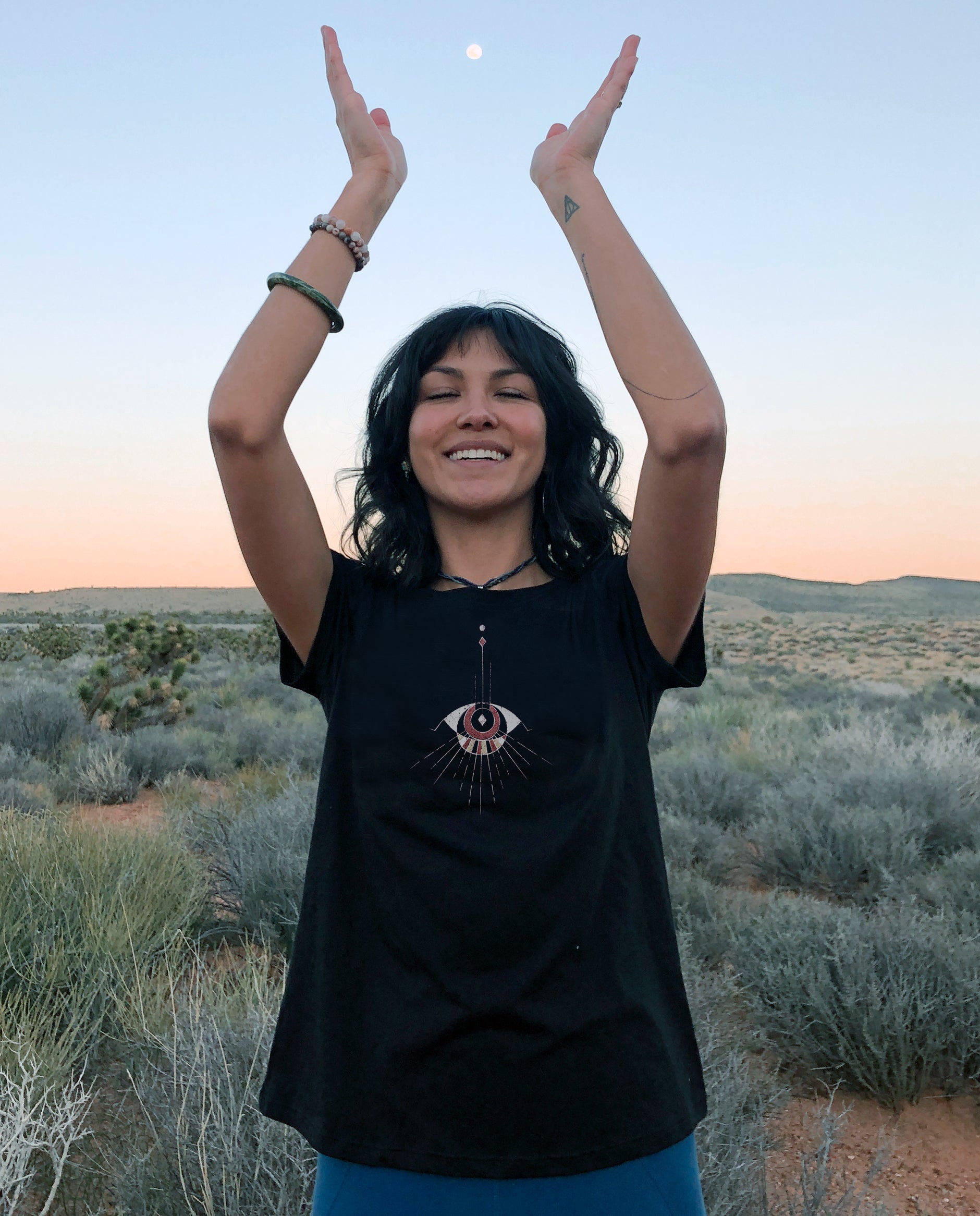 Women wearing comfortable Black Unisex T, Poly Cotton blend.  Abstract Eye pattern draping from neckline.