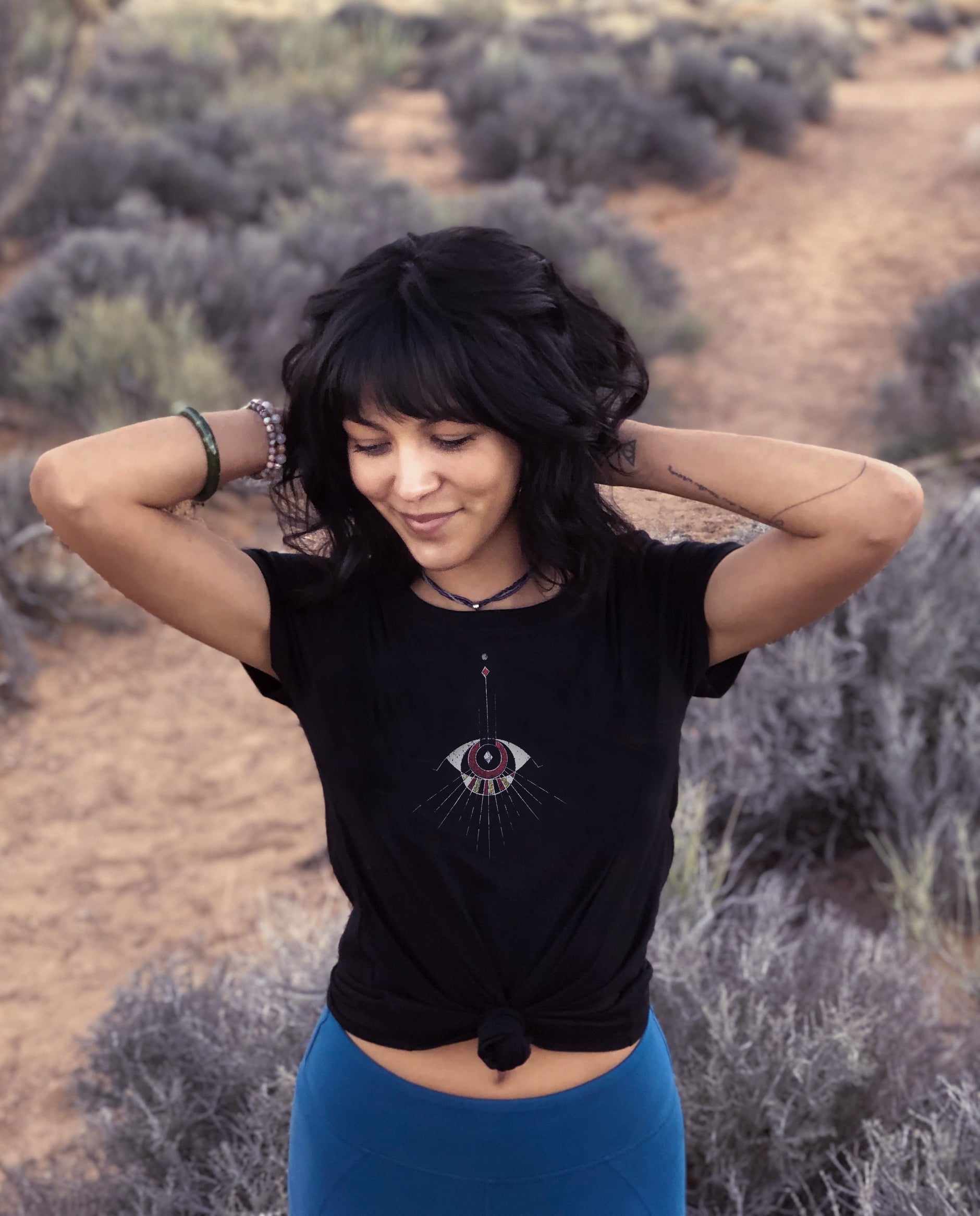 Women wearing comfortable Black Unisex T, Poly Cotton blend. Abstract Eye pattern draping from neckline.